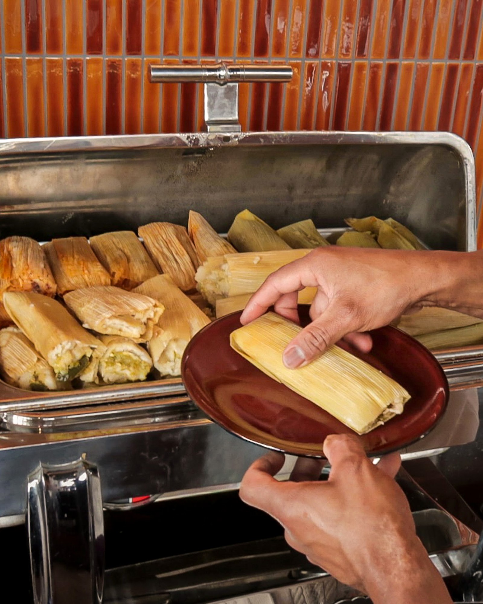 Hands plating a tamal from the chafing dish buffet